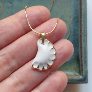 a white porcelain dumpling, gilded, on a chain